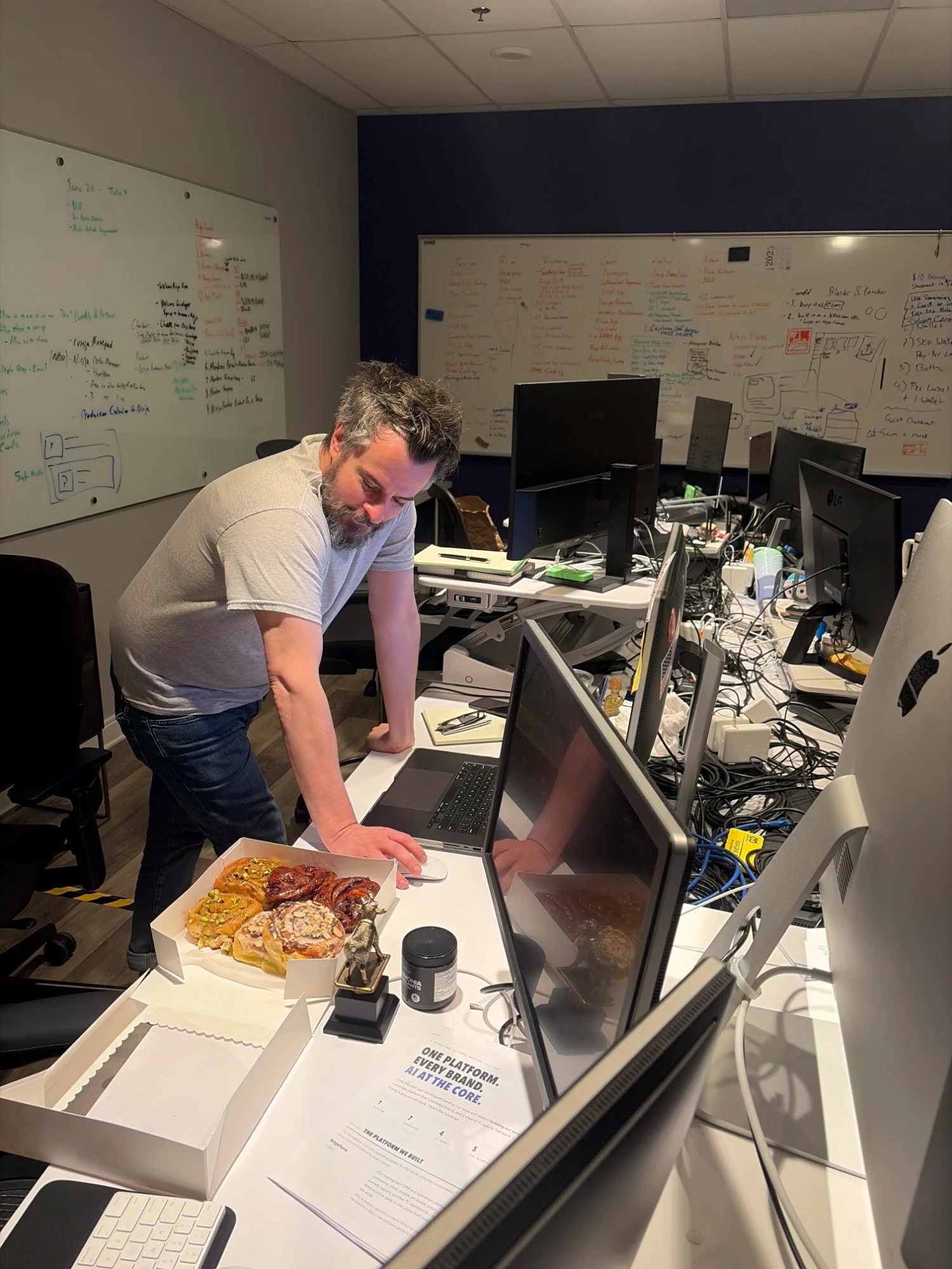 Leaning over a desk with a box of pastries